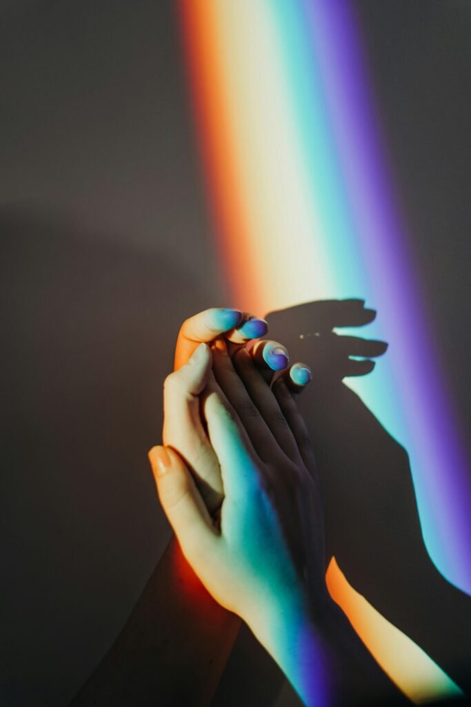 Artistic representation of unity with hands holding under colorful rainbow light reflection.